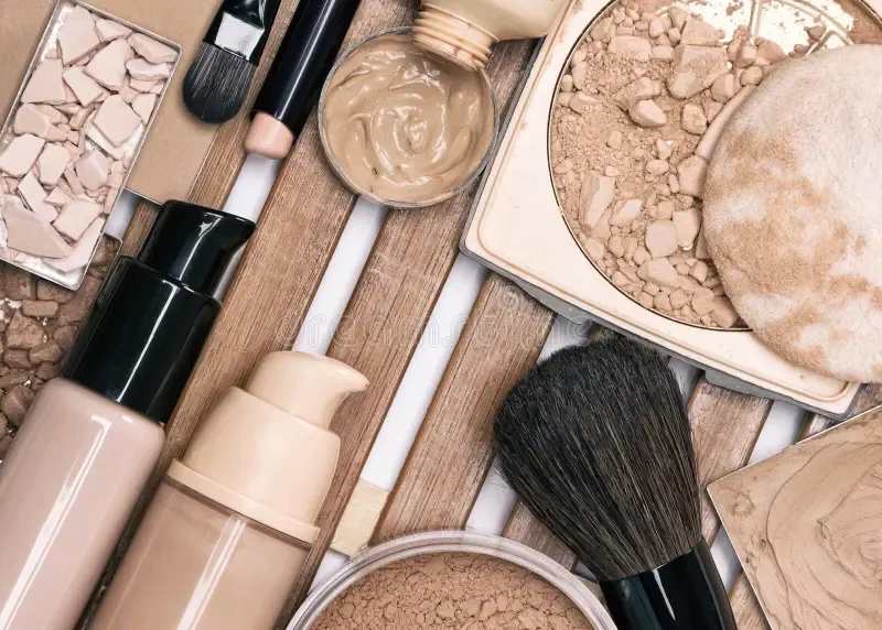 Foundation, powder, and makeup brushes arranged on a wooden surface