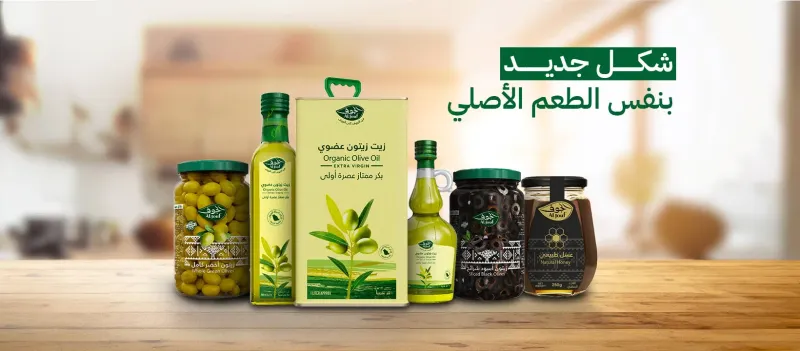 Al Jouf branded olive oil, olives, and honey products displayed on a wooden counter
