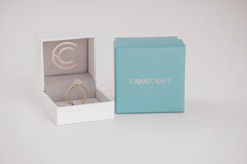 Diamond ring in a jewelry box next to CaratCraft-branded packaging