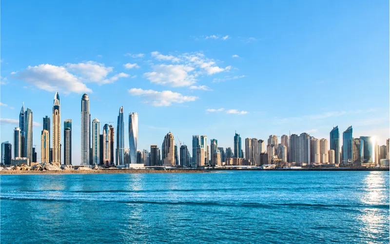 Modern high-rise towers along a waterfront under a clear blue sky